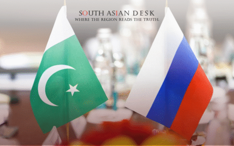 Two small flags, one of Pakistan with a green background, white stripe, crescent moon, and star, and the other of Russia with white, blue, and red vertical stripes, placed on a table with blurred bottles and decorations in the background.