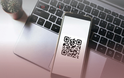 A smartphone displaying a QR code placed on a laptop keyboard next to a small potted cactus on a white surface.