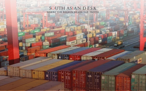 A busy port with numerous colorful shipping containers stacked high, red cranes overhead, and a cityscape in the background.