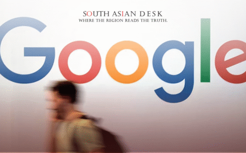 A large Google logo with multicolored letters on a white wall, with a blurred person walking in front carrying a backpack.