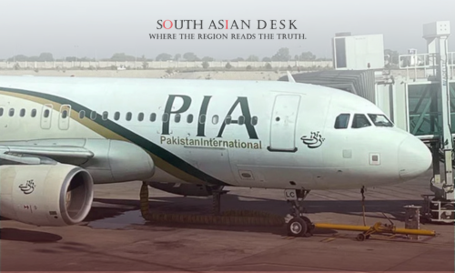 A Pakistan International Airlines (PIA) airplane parked at an airport gate, with the airline's logo and name visible on the fuselage, connected to a jet bridge.