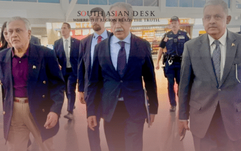 A group of men in suits walking through an airport terminal, accompanied by security personnel.