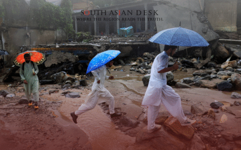 Three men in white traditional attire holding an umbrella and crossing a water stream