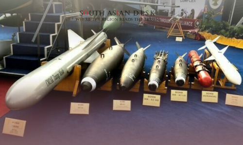 Display of various bombs and missiles on stands set against a backdrop of an aircraft and exhibition signage during Pakistan-UK defence Cooperation