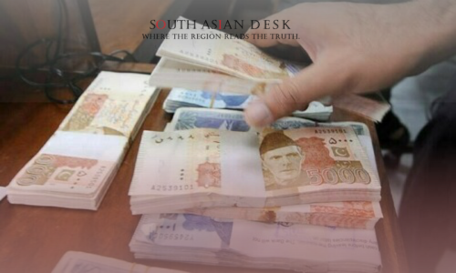 A male hand stacking Pakistani Currency Bundles collected from Graft scandal