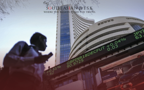 Indian man holding phone looking at stocks prices as Indian stock exchange dips