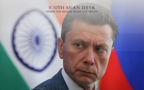 man in suit looking to the side, with indian and russian flags blurred in the background